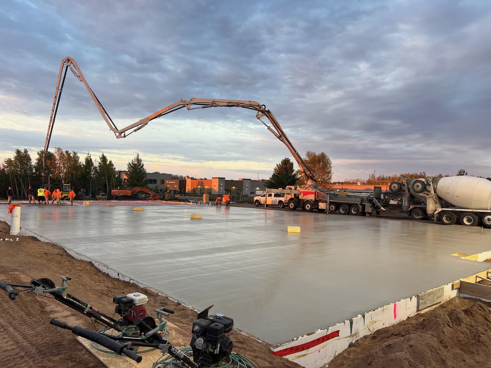Primetime Concrete crew pouring a large slab at sunset with pump truck arching overhead